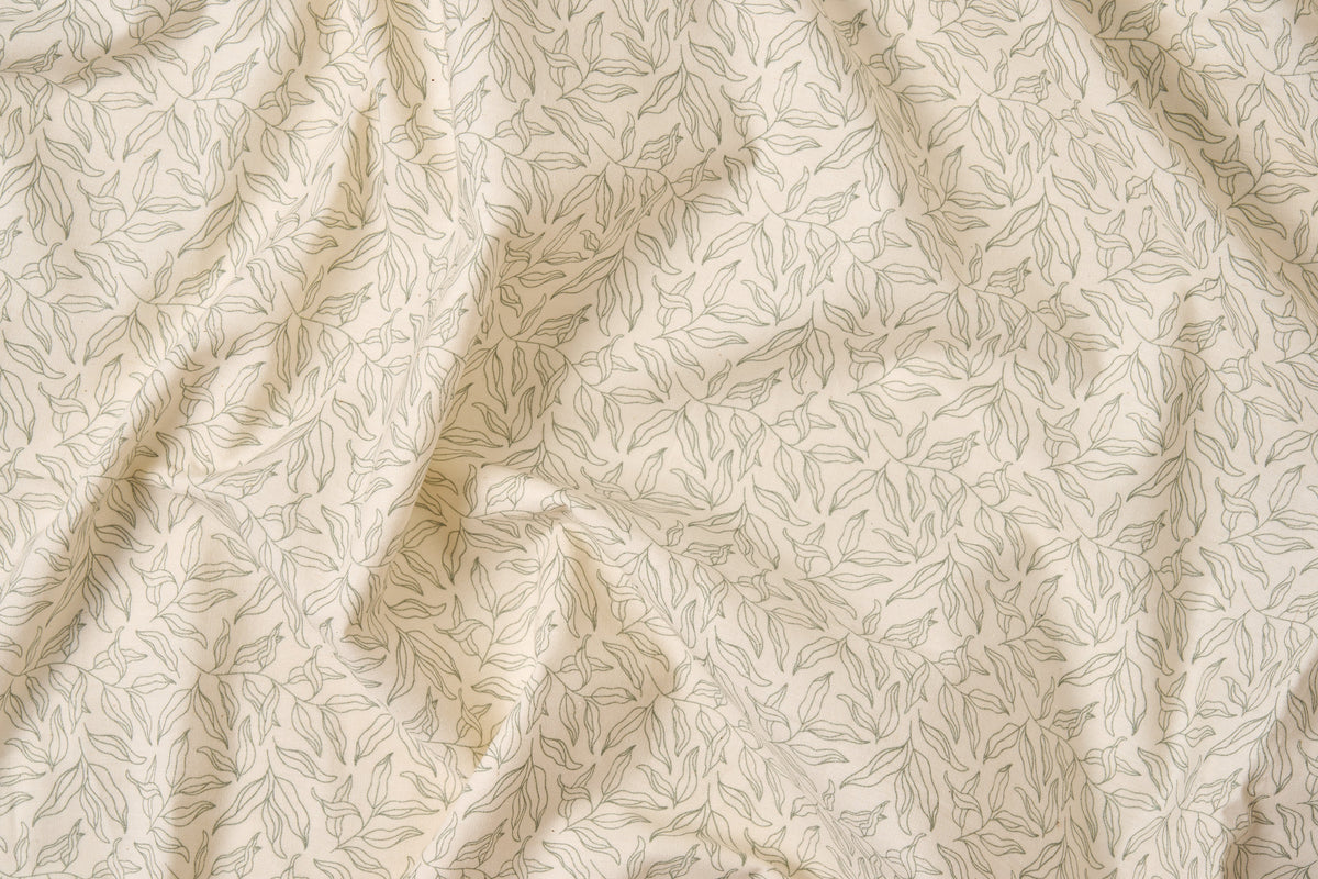 Green leaf print cotton bed sheet set by American Blossom Linens, close-up of natural background fabric.