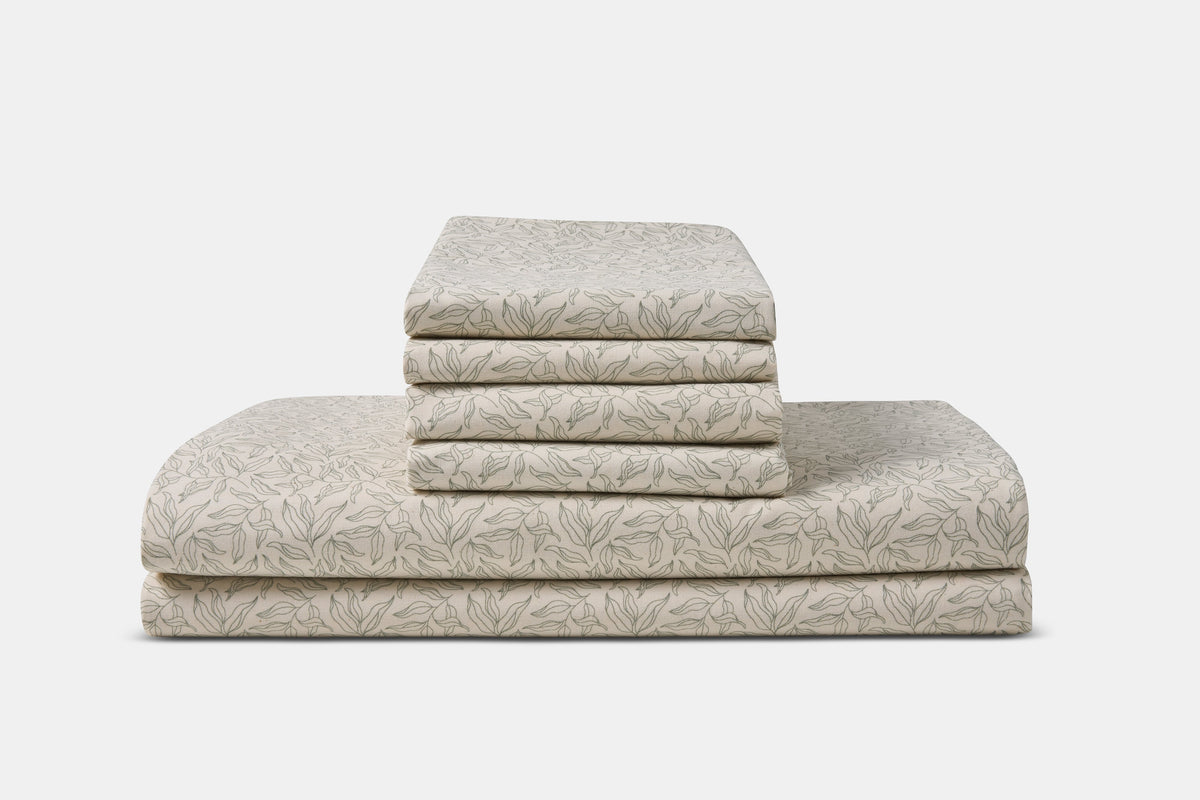 American Blossom Linens cotton bed sheet set with green leaf print on a natural background, showcasing soft, breathable fabric.