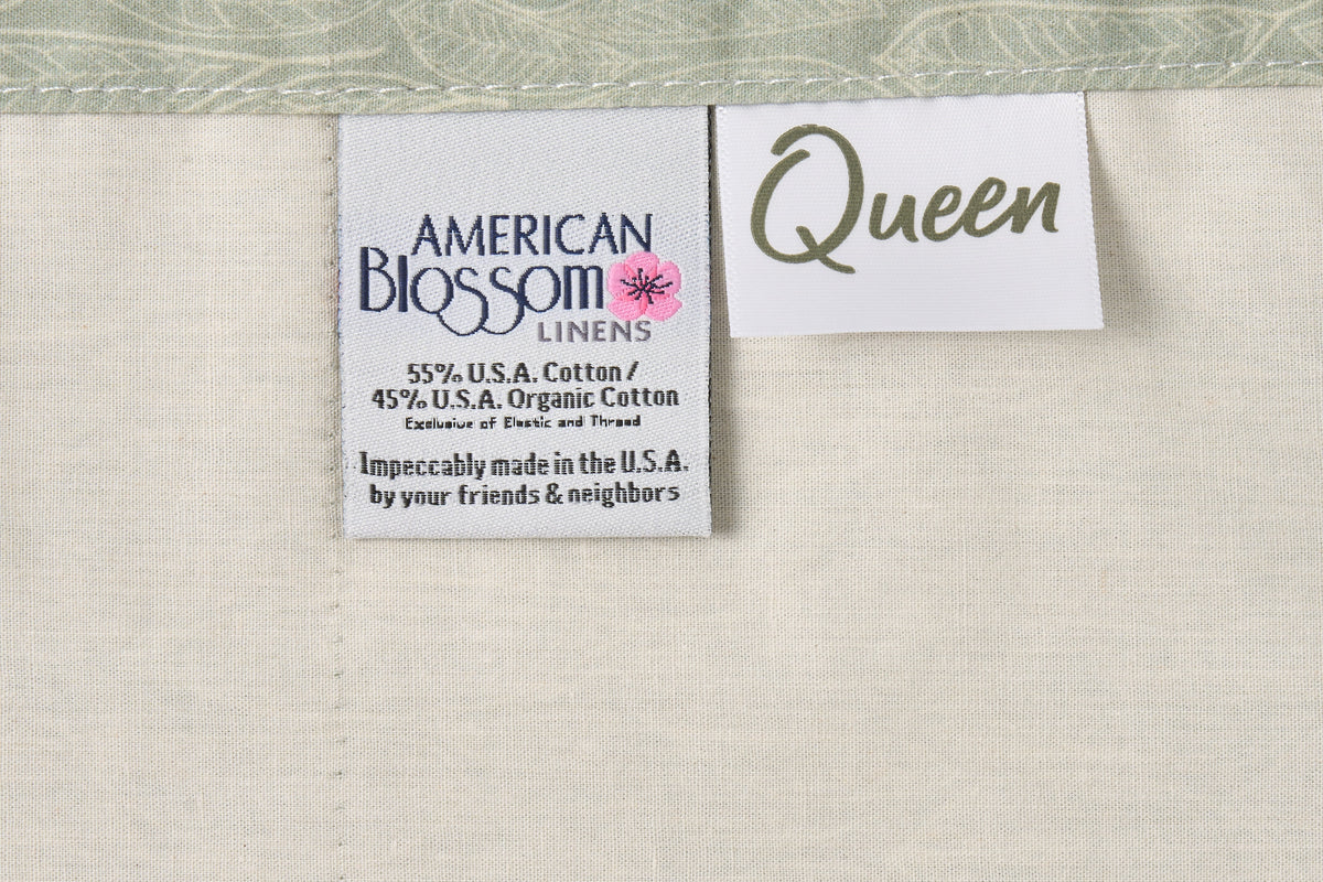 Cotton bed sheet set with leaf print on green background from American Blossom Linens, includes size and contents labels.
