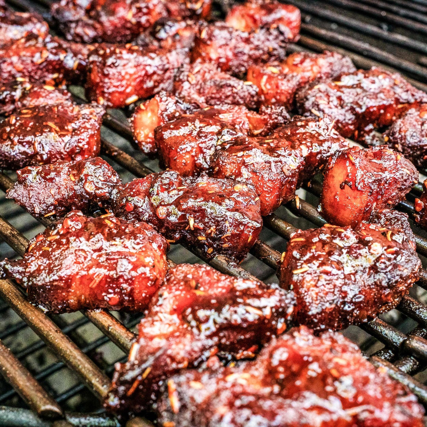 Pig of the Month BBQ smoked beef brisket burnt ends sizzling on the grill, showcasing crispy, melt-in-your-mouth BBQ chunks.