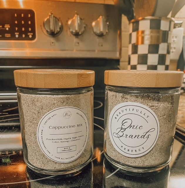 Onic Brands LLC cappuccino drink mix in a container, with a scoop of prepared cappuccino showing frothy top and coffee powder.