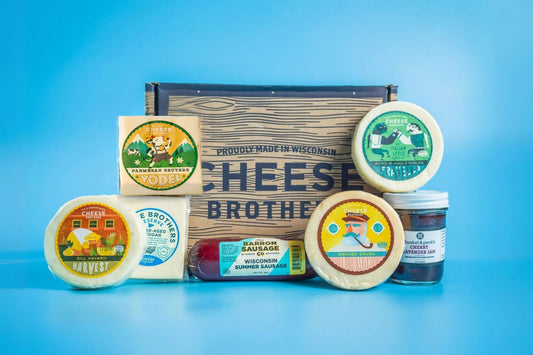 Assorted charcuterie meats, cheeses, and crackers arranged in a gift box by Cheese Brothers Inc. for a gourmet gift bundle.