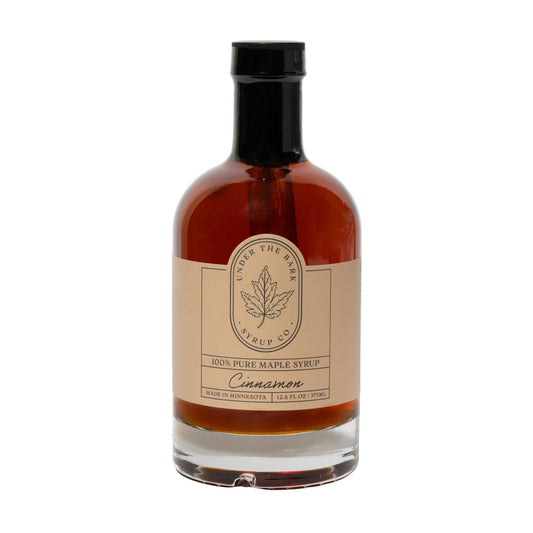 12oz bottle of cinnamon maple syrup from Under The Bark Syrup Co, showing a rich, amber-colored syrup in a clear glass bottle.