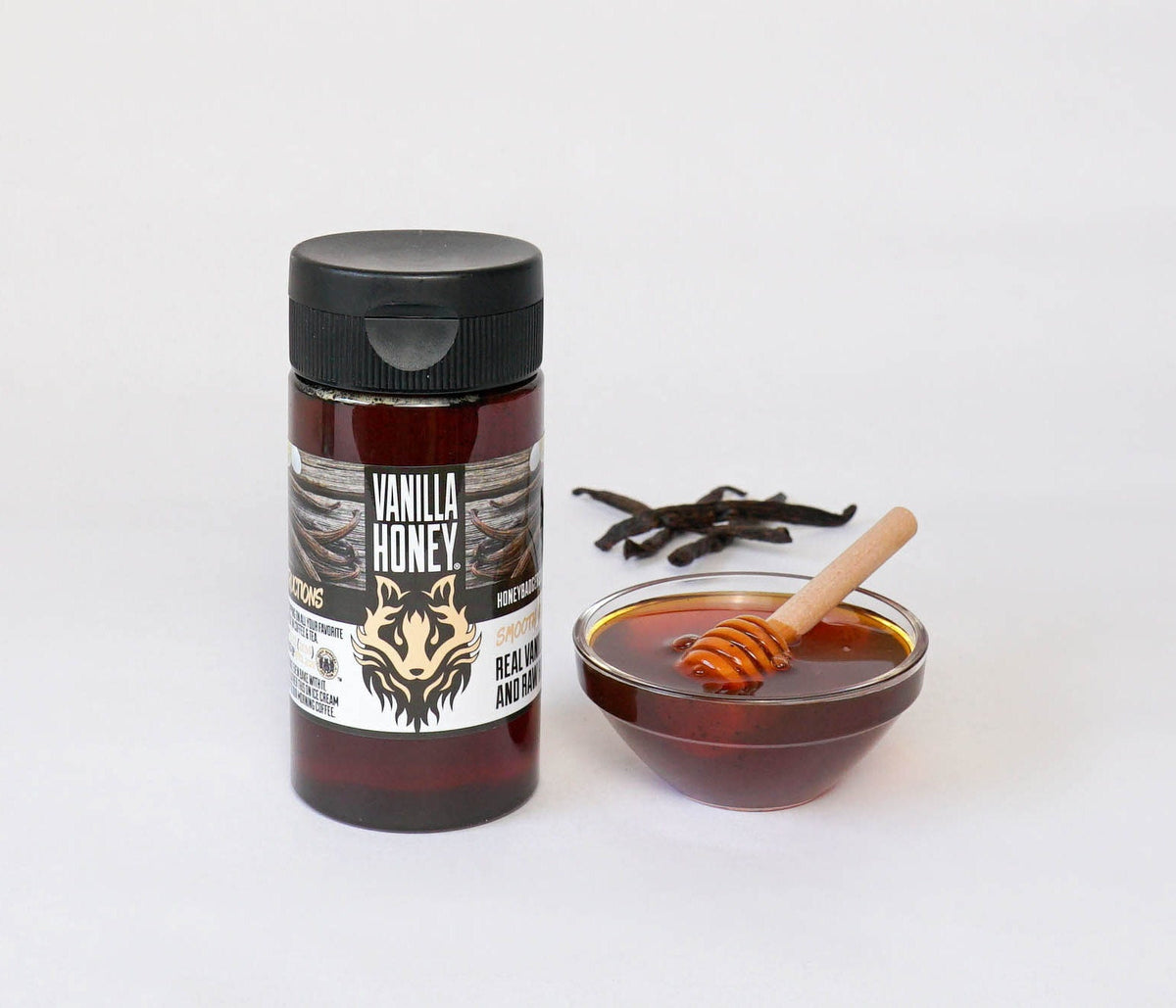 Glass jar of vanilla honey from Honey Badgers Bee Farm with a golden honey inside and vanilla bean visible.