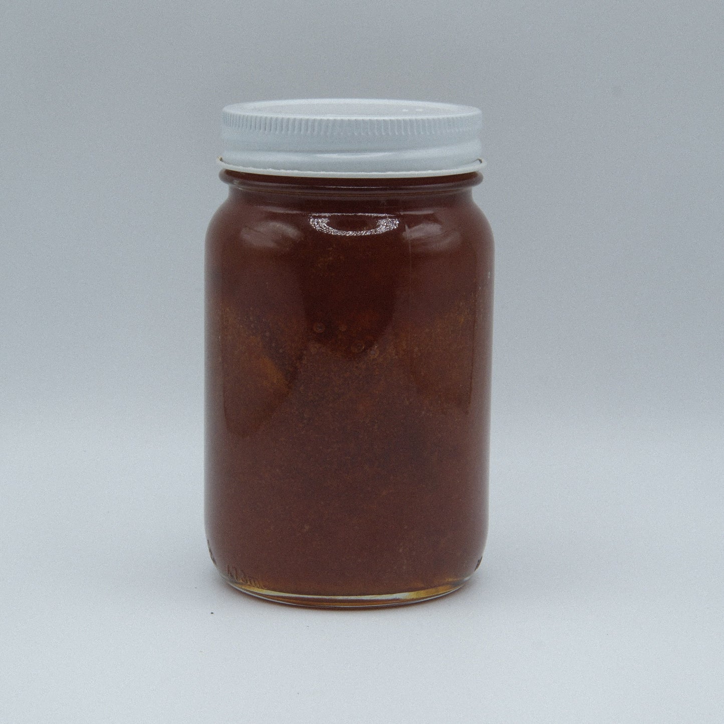 Amish Miller’s Apricot Jam jar with vibrant apricot spread, displayed on a rustic wooden surface.