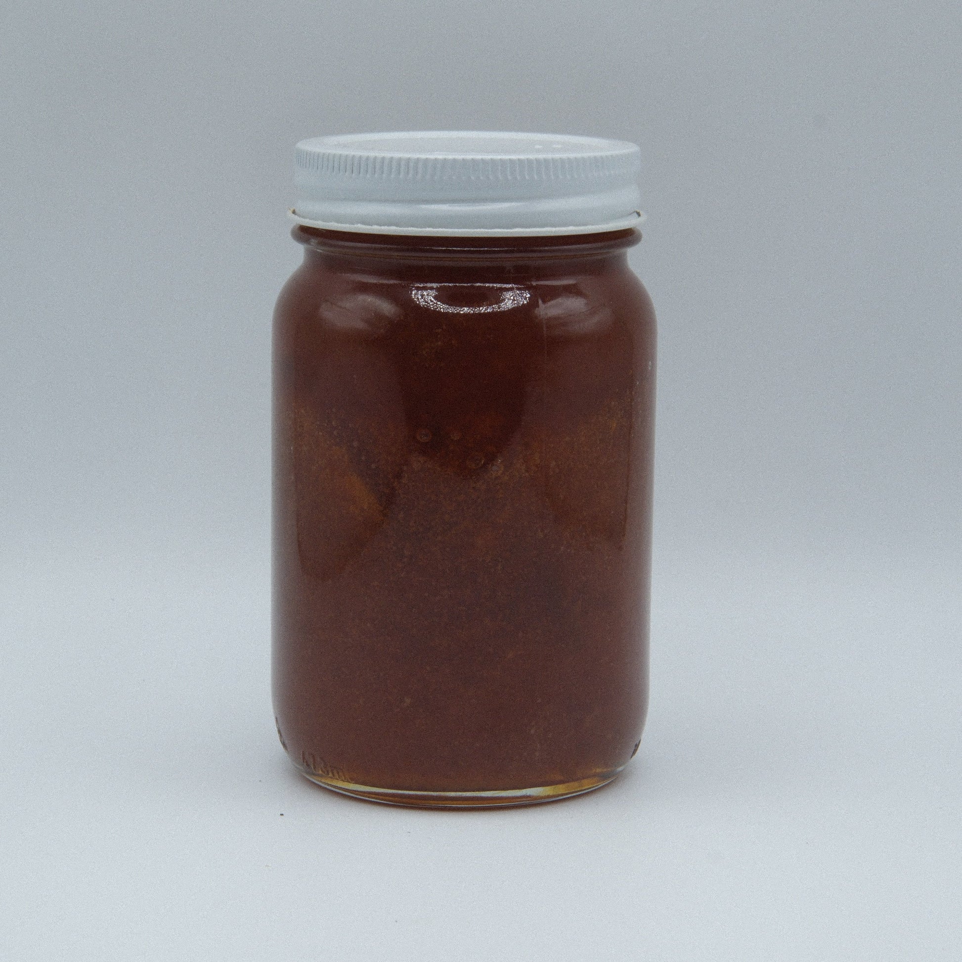Amish Miller’s Apricot Jam jar with vibrant apricot spread, displayed on a rustic wooden surface.