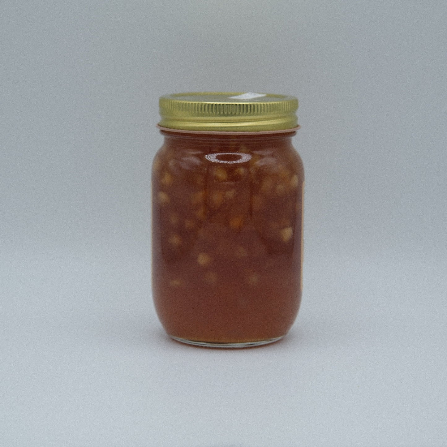 Canned Apple Pie Jam by Amish Country Store in a jar, showcasing glossy apple and spice filling with a golden hue.