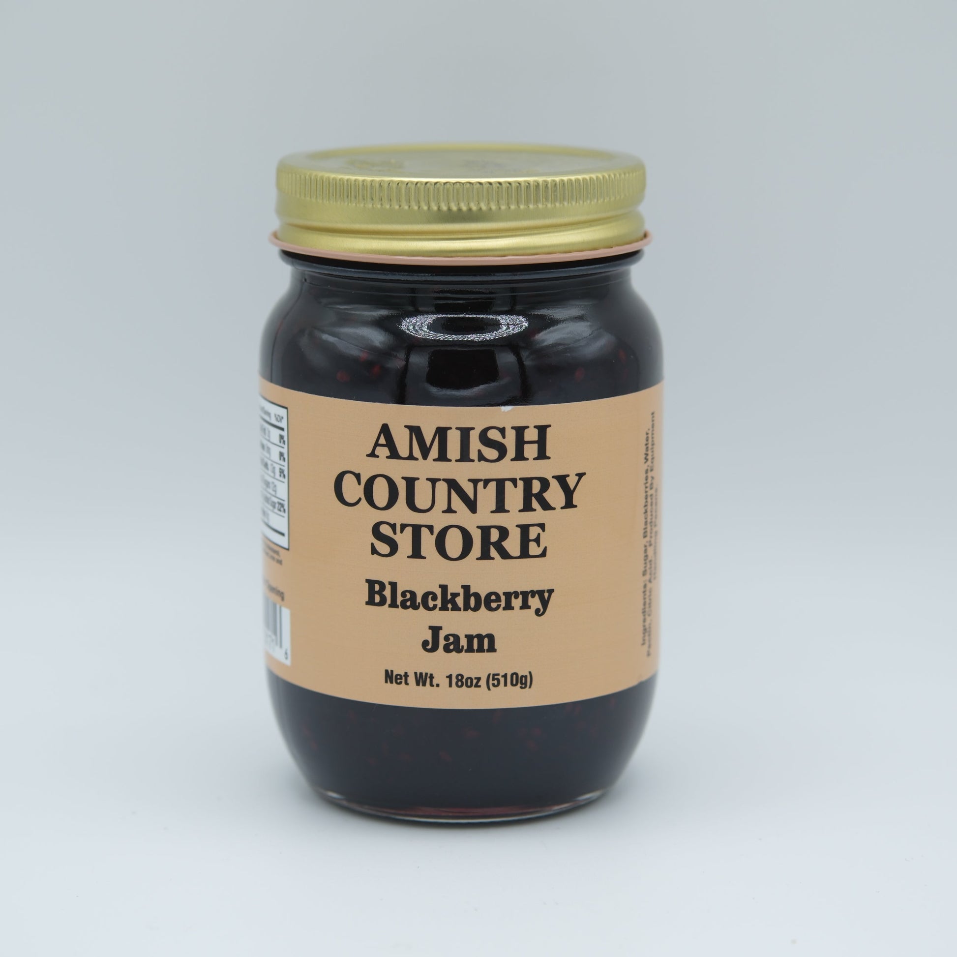 Canned Amish Country Store blackberry jam jar, 18 oz with a label, glossy lid, and fresh blackberry fruit visible inside.