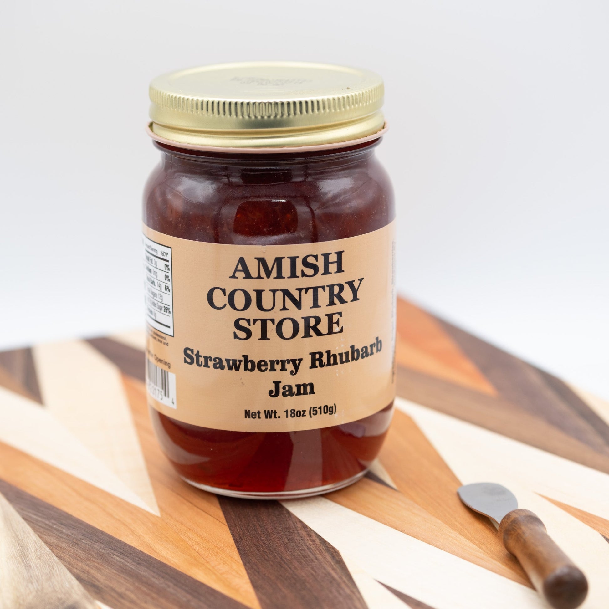 Canned Strawberry Rhubarb Jam jar from Amish Country Store, showing the label and sealed lid in a close-up view