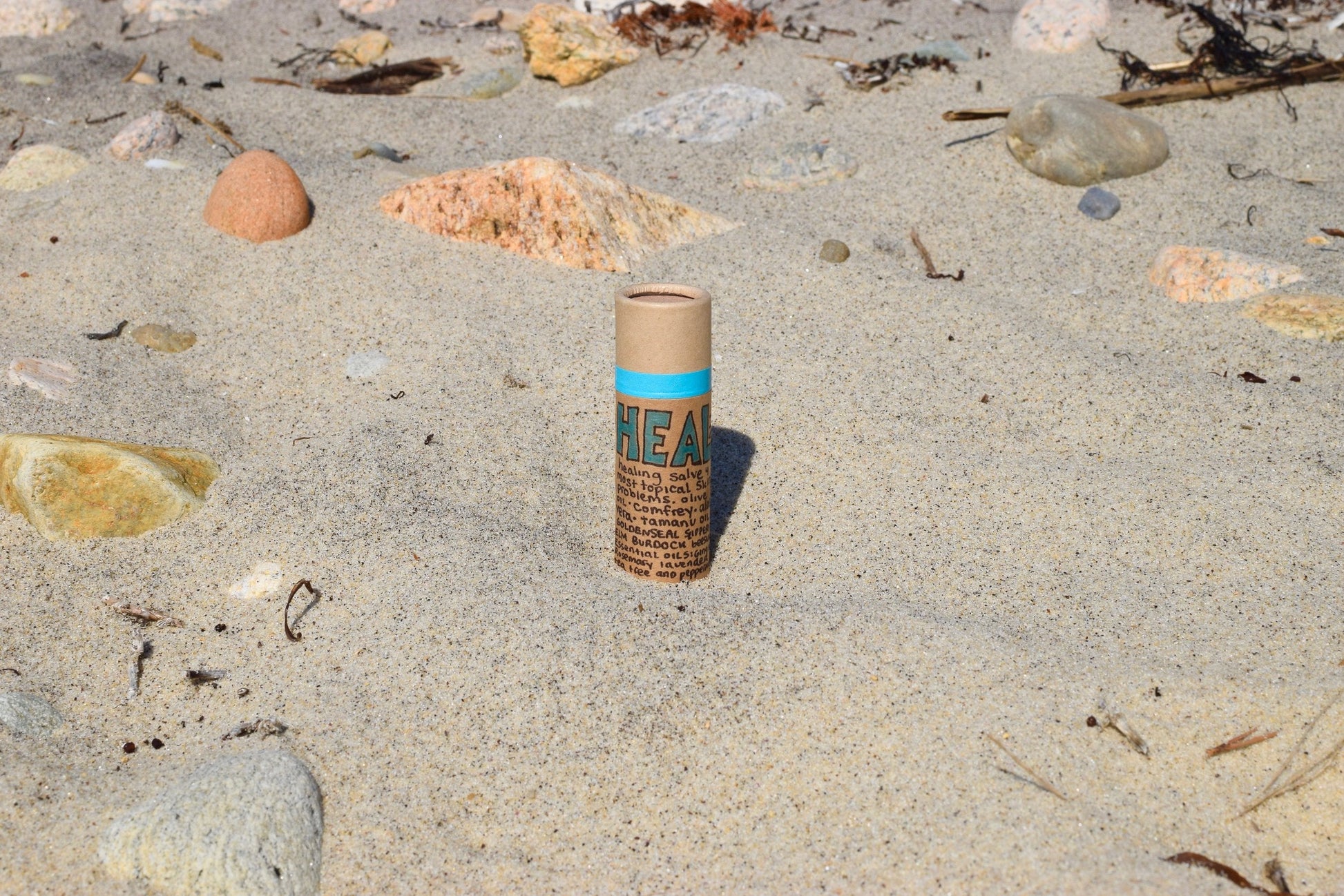 Plant Makeup Heal All Balm jar with natural herbal ingredients and a white lid, placed on a wooden surface.