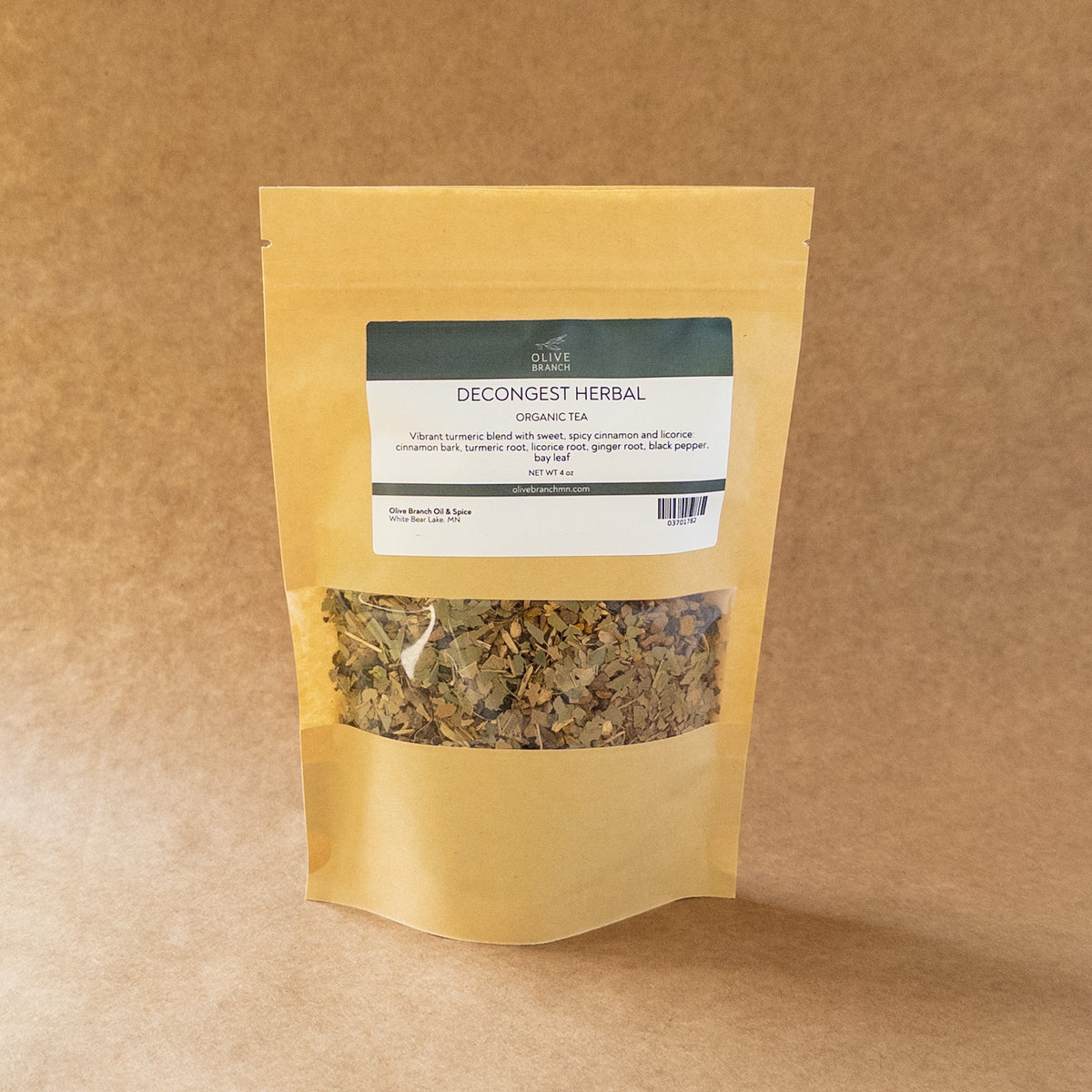 Decongest herbal tea from Olive Branch Oil & Spice, featuring fresh herbs in a clear glass cup on a wooden surface.