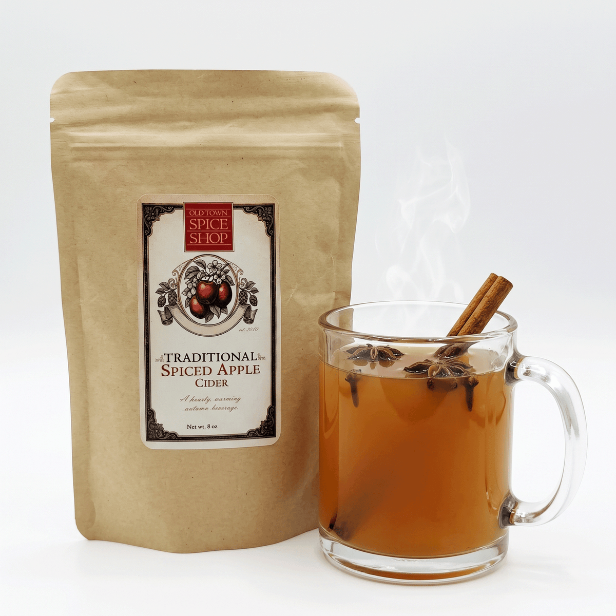 Bottle of Old Town Spice Shop spiced apple cider with cinnamon and spices, ready to serve in a clear glass mug.