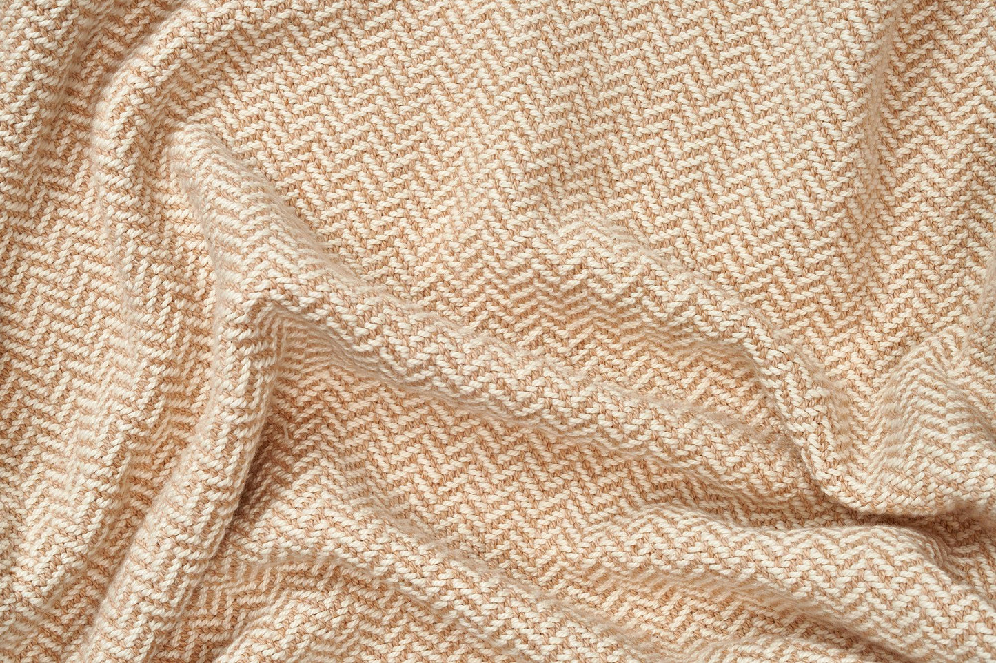 Folded American Blossom Linens cotton blanket with herringbone weave, showcasing textured fabric in natural hues.