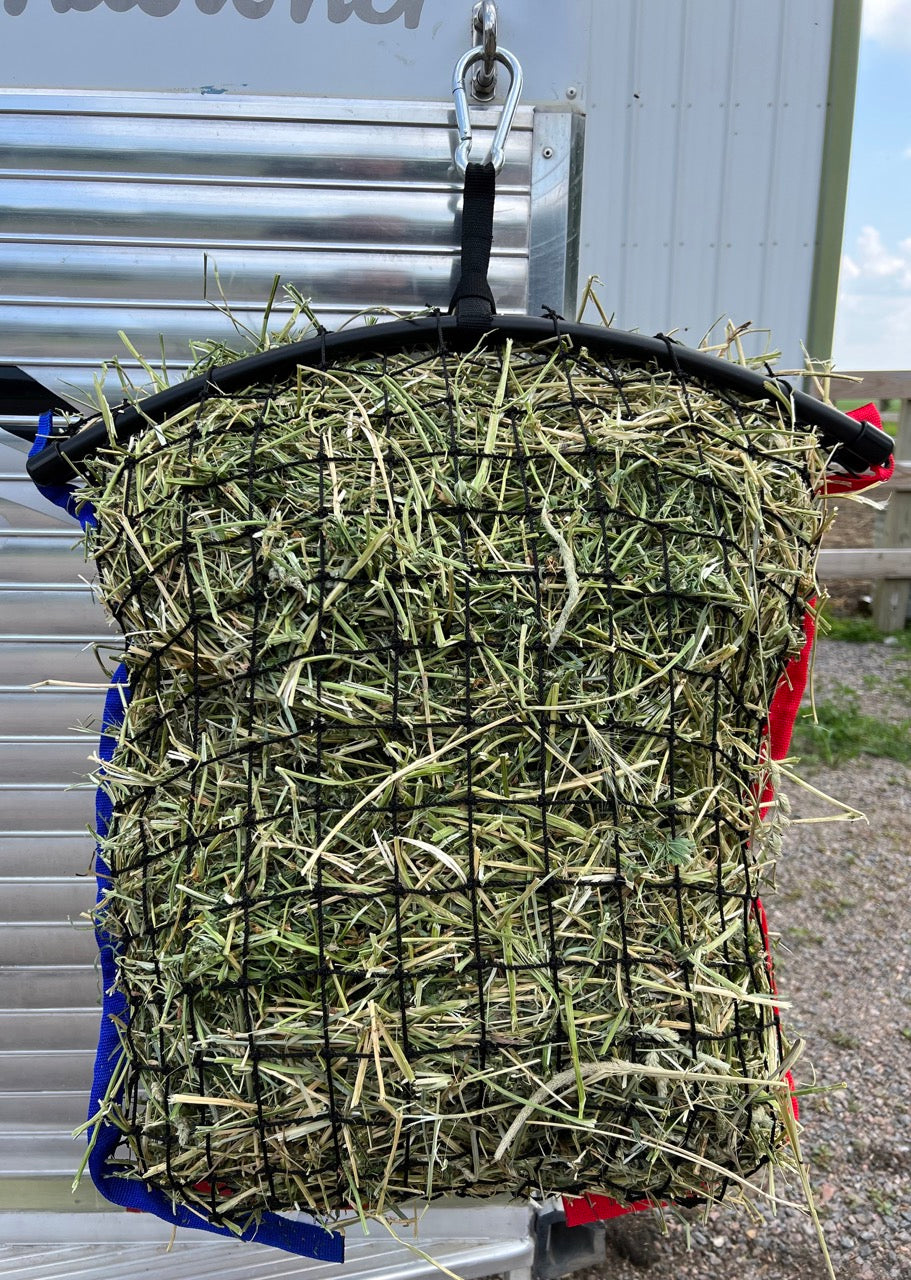 Limited edition Haylo Haynets LLC Freedom haynet hanging in a stable stall, showcasing durable mesh design for feeding hay.