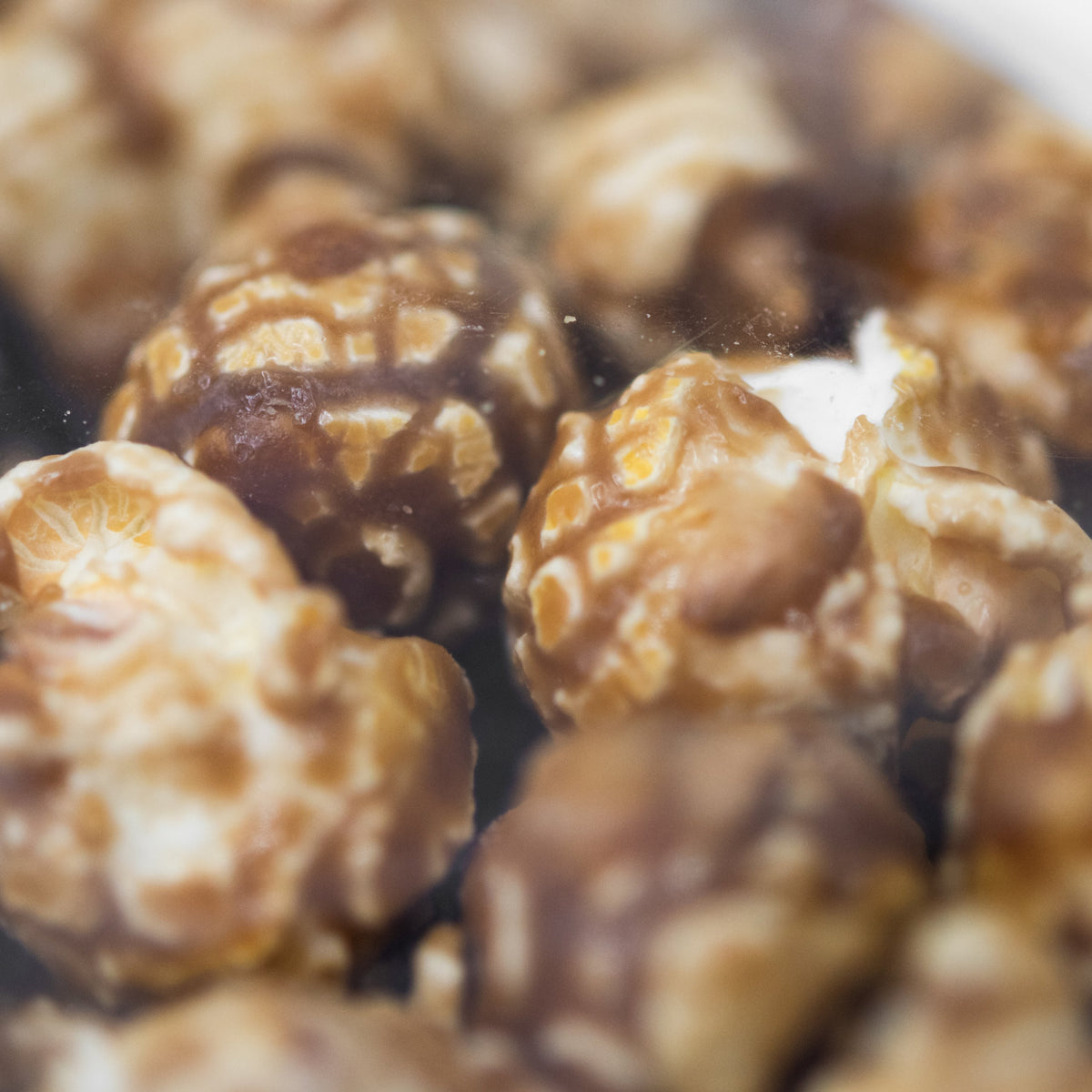 Crunchy caramel popcorn in an 8 oz bag by HR Poppin' Snacks, featuring golden caramel-coated popcorn kernels.