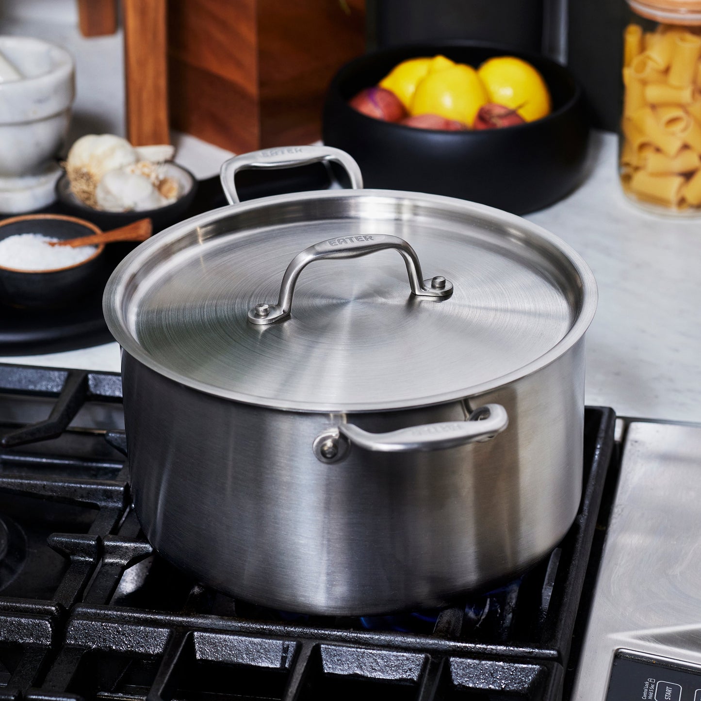 Heritage Steel Eater 8 Quart Stock Pot with lid, stainless steel cookware for soups and stews, on stovetop.