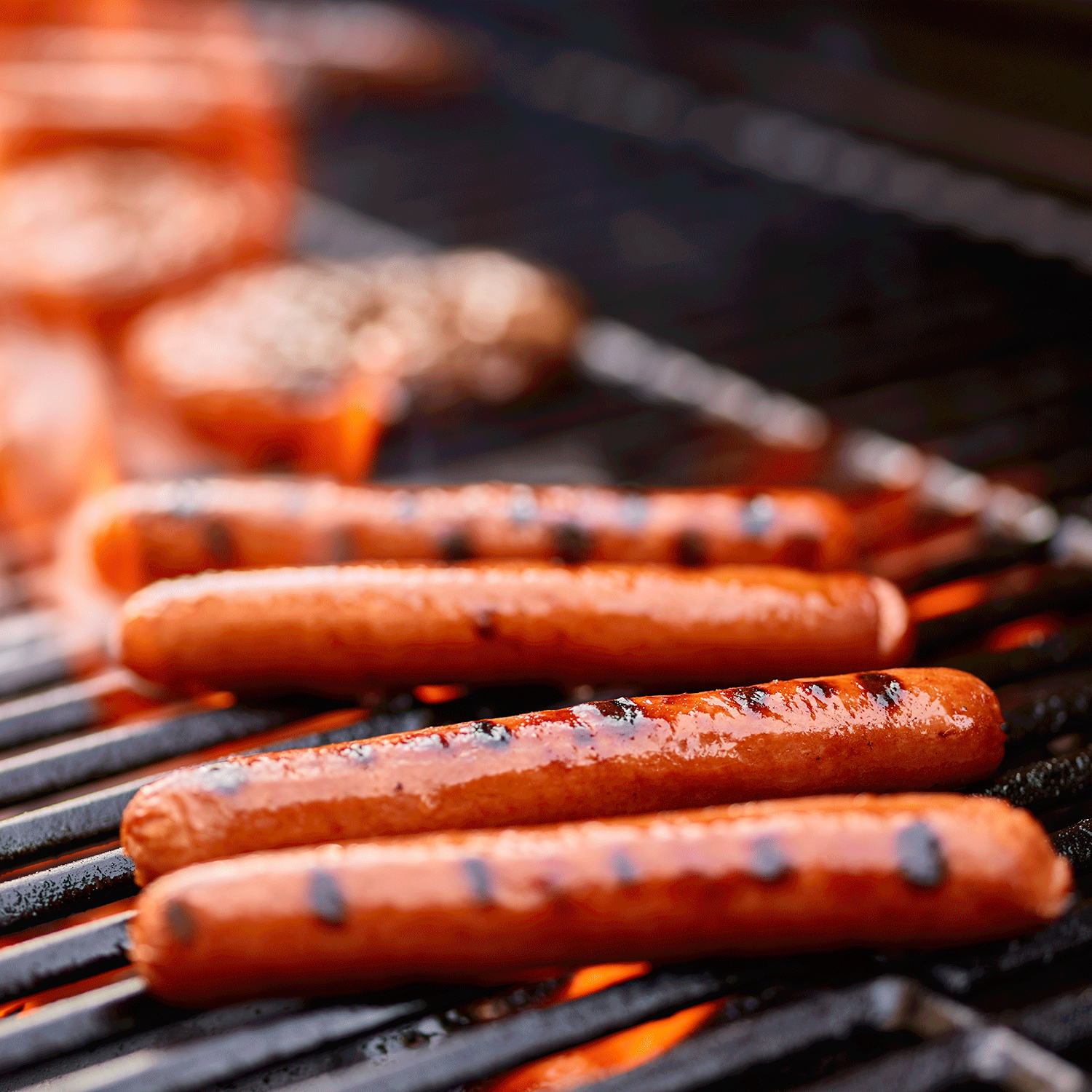 Juicy grass-fed beef hot dogs grilling on a barbecue, jumbo gourmet all-beef franks ready to be served.
