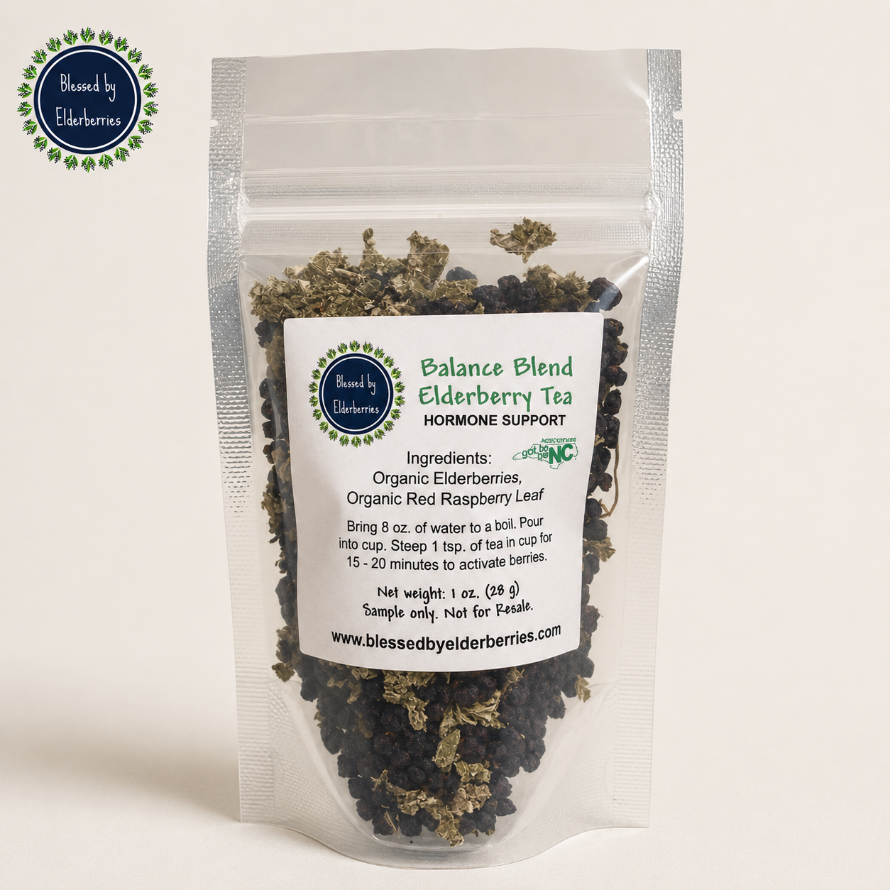 Blessed by Elderberries Balance Blend Elderberry tea in a clear glass cup with fresh elderberries and herbs.