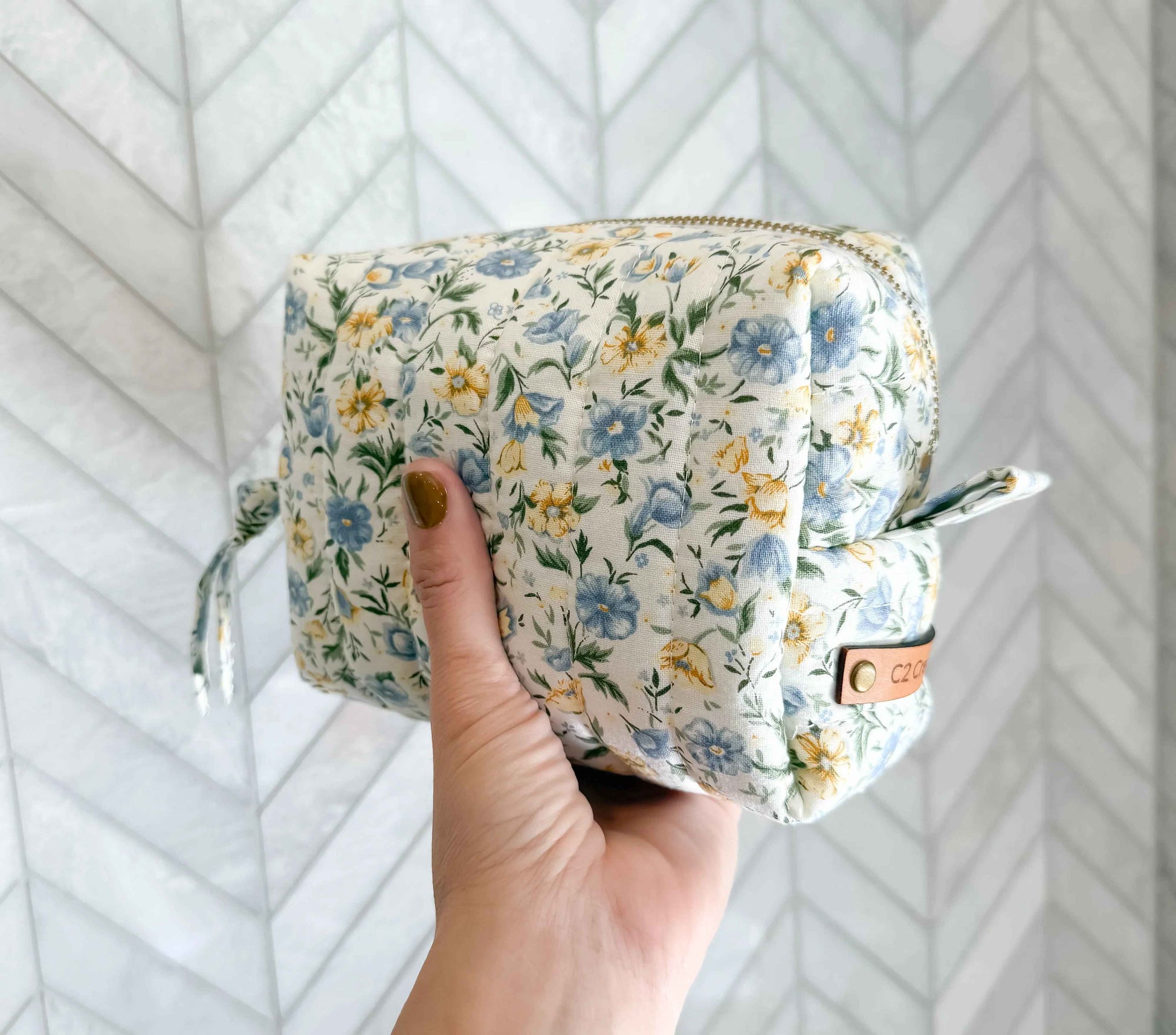 Handmade floral makeup bag with blue and yellow garden pattern by C2 Creations LLC, featuring a zippered toiletry bag design.