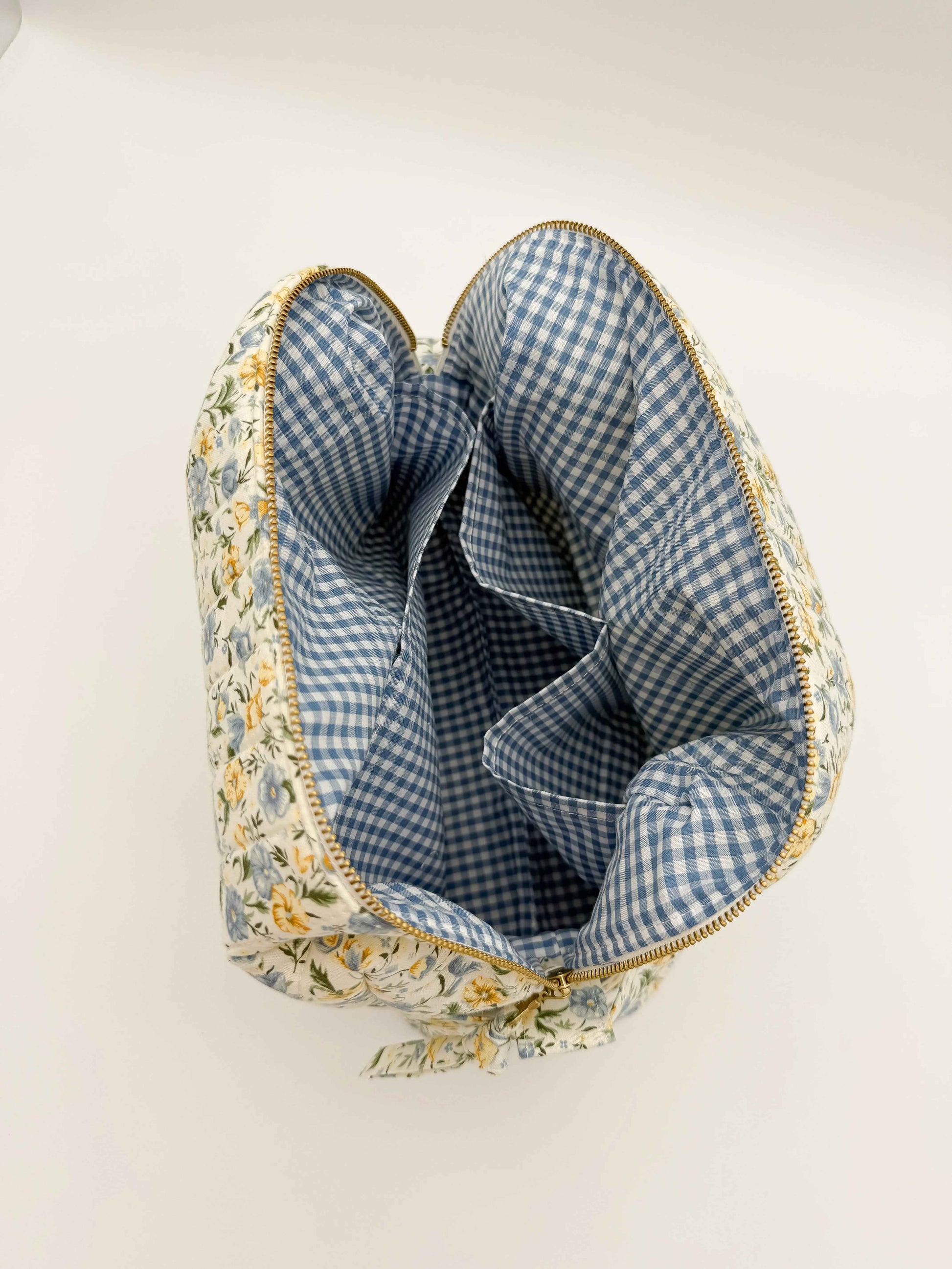 Handmade floral makeup bag by C2 Creations LLC with blue and yellow garden pattern toiletry bag on a white background.
