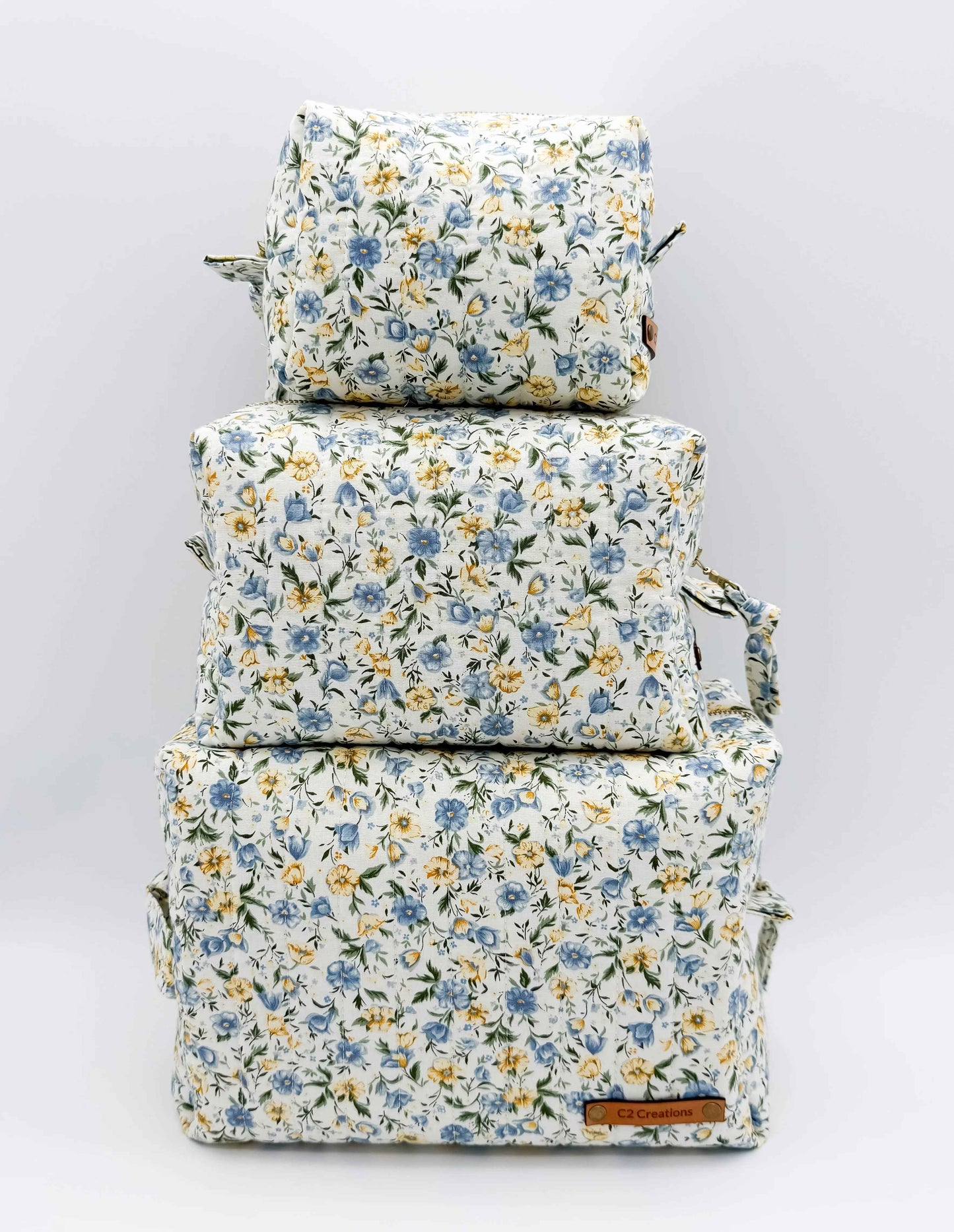 Handmade floral makeup bag by C2 Creations LLC with blue and yellow garden pattern, featuring a toiletry bag design.