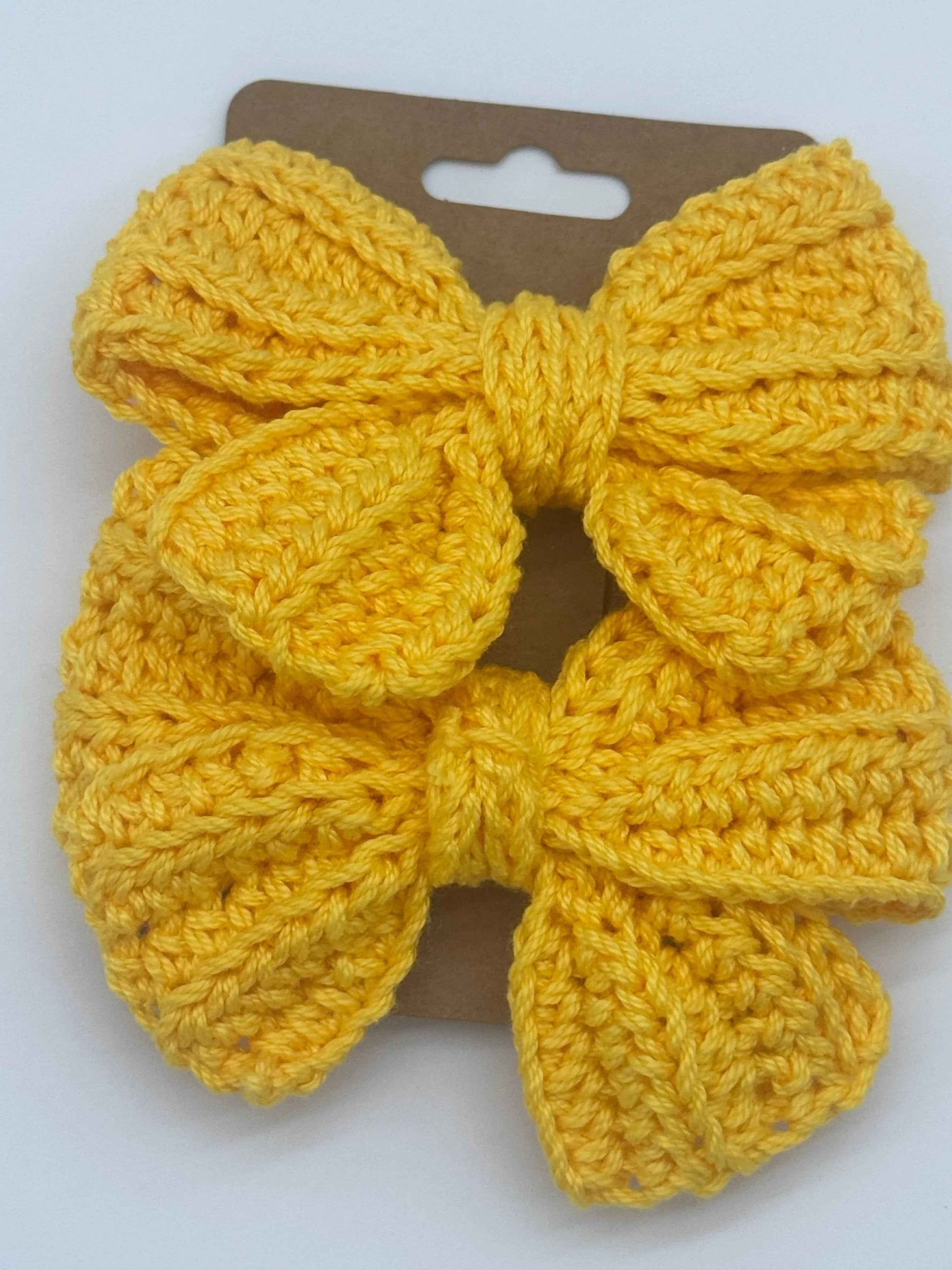 Handcrafted crochet bow hair accessory by C2 Creations LLC featuring colorful, textured yarn and a secure alligator clip attachment.