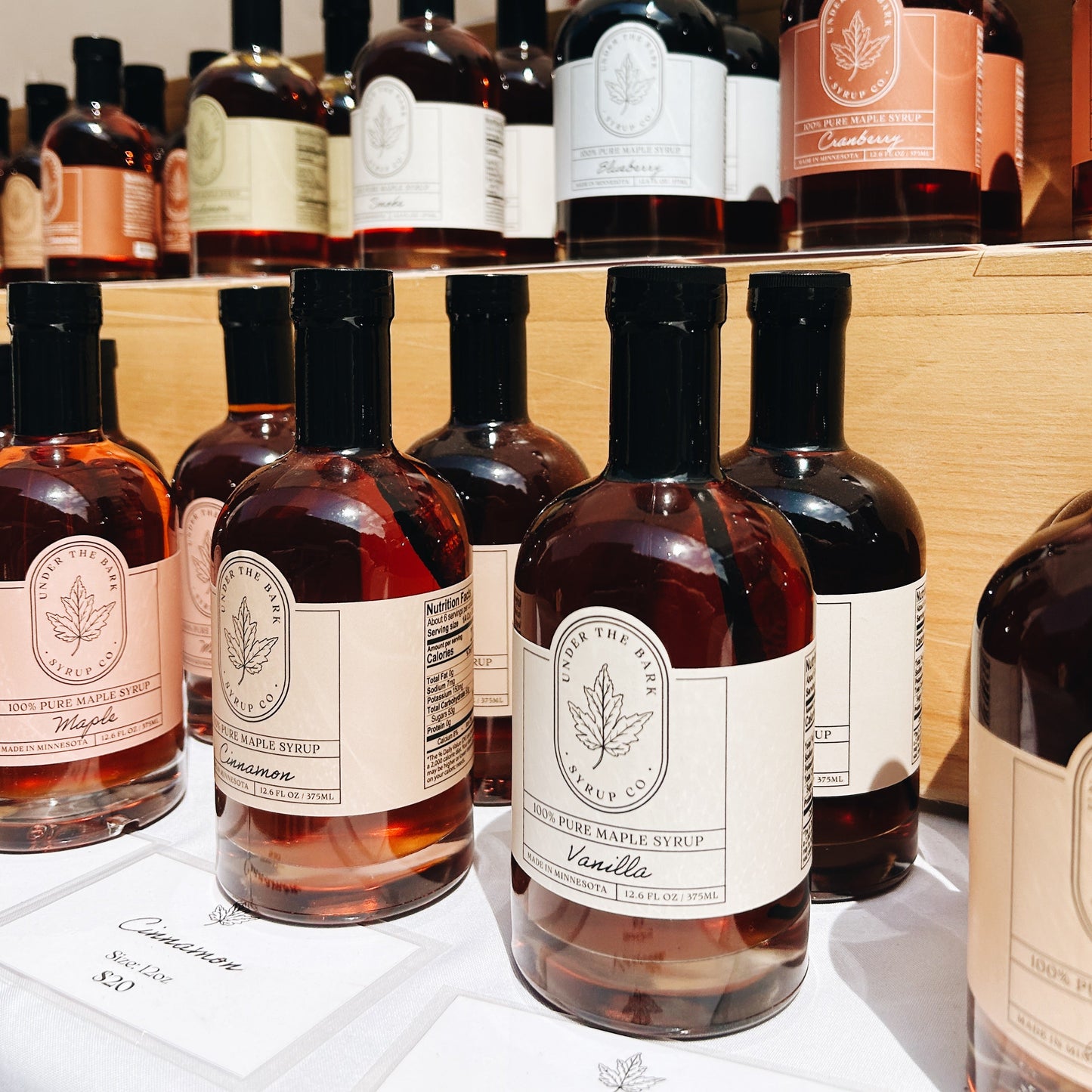 Bottle of Cinnamon Maple Syrup from Under The Bark Syrup Co, with a clear label and amber syrup inside.