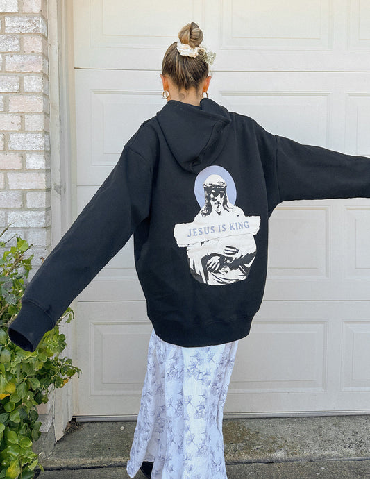 Black unisex hoodie featuring a Jesus Is King graphic design by Elevated Faith, casual wear with religious imagery and comfortable fit.