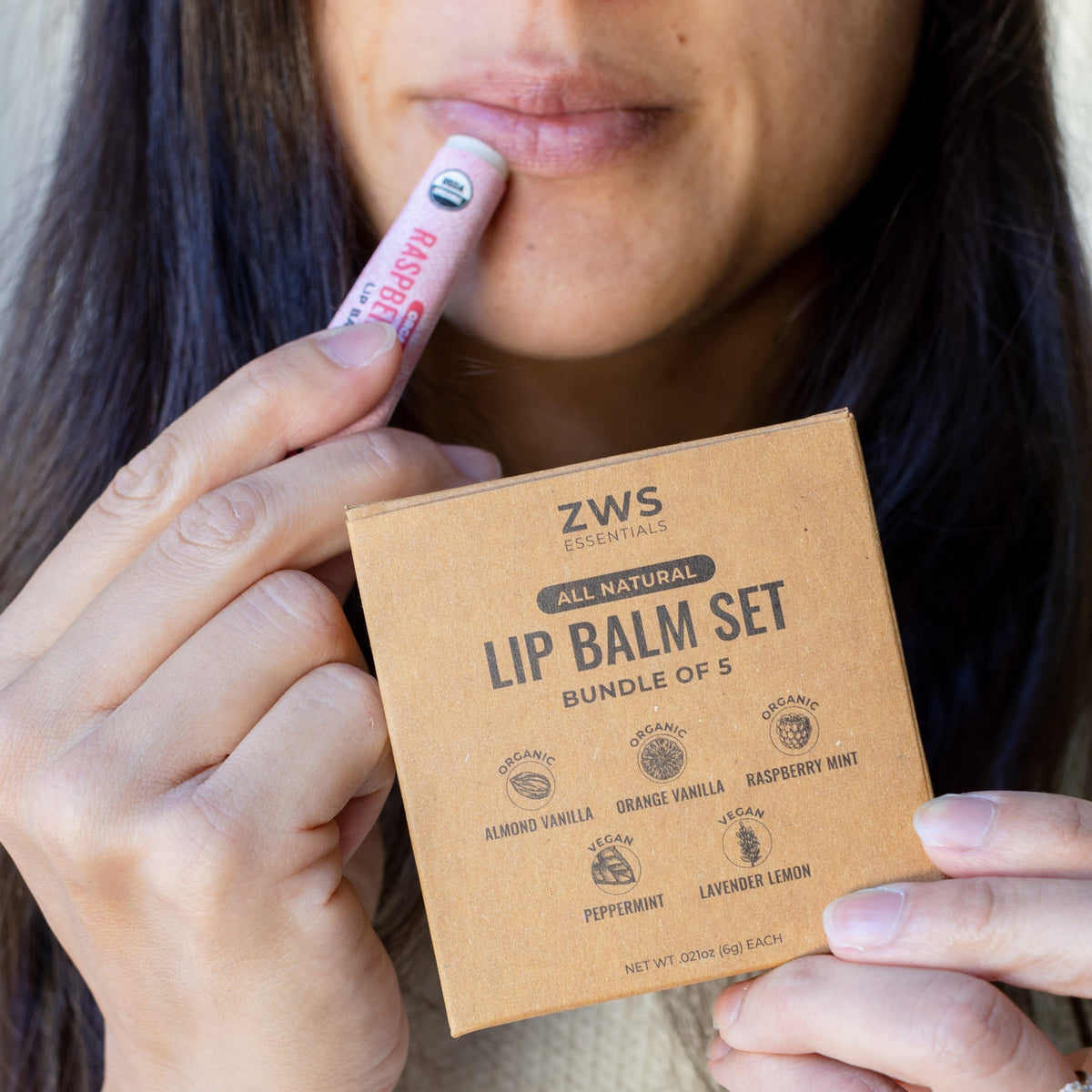 All natural lip balm set with multiple flavors in small containers, displayed on a wooden surface with greenery in the background.