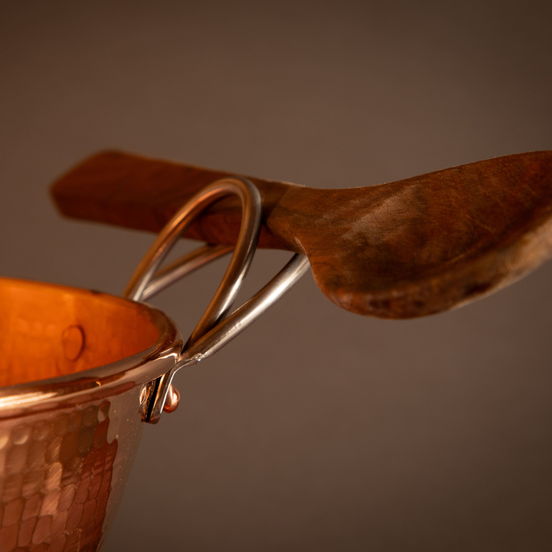 Set of Sertodo copper mixing bowls with a spoon for baking and cooking, showcasing shiny, hammered copper surfaces.