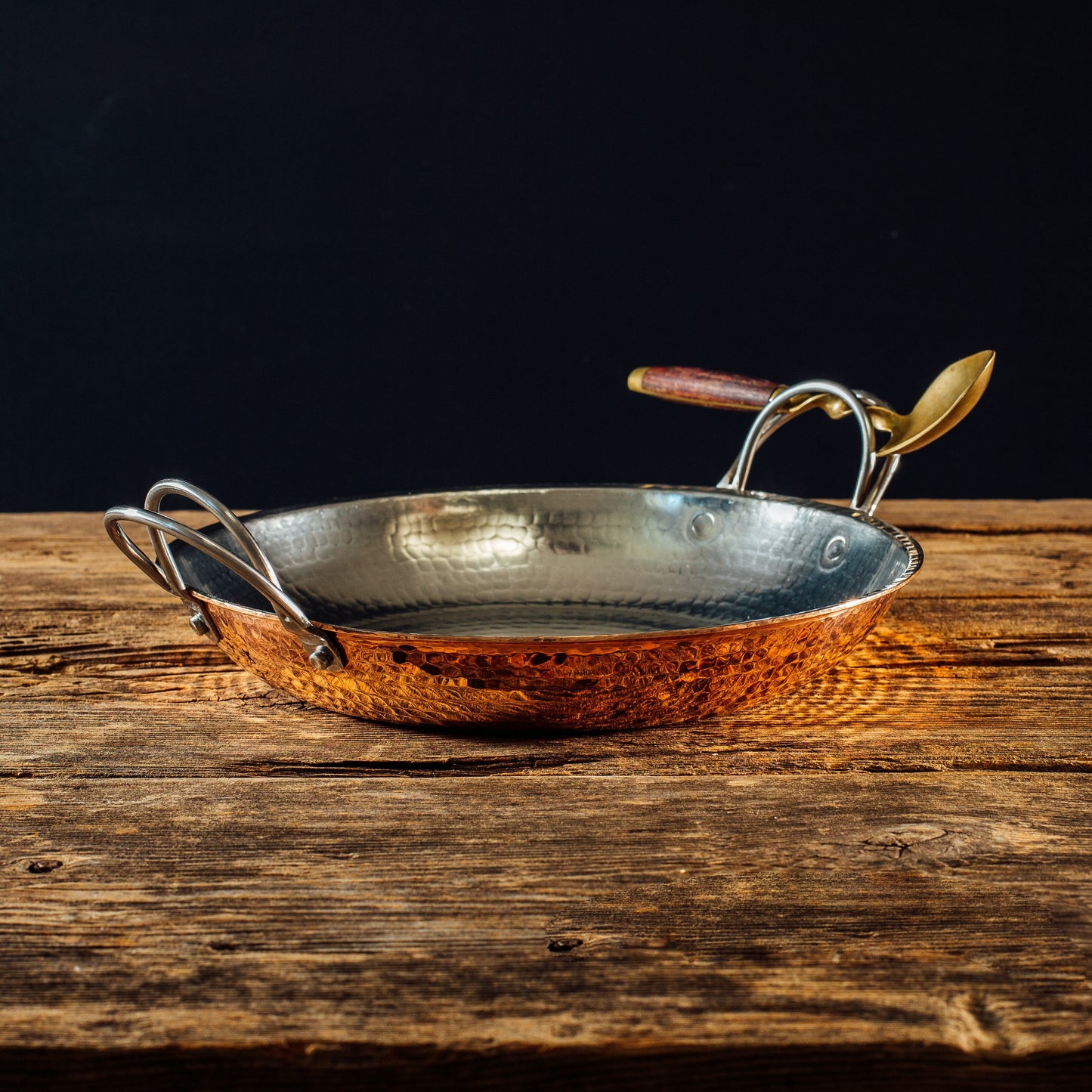 Sertodo Alicante Copper Paella Pan with a wooden ladle, showcasing a traditional round pot ideal for cooking paella.
