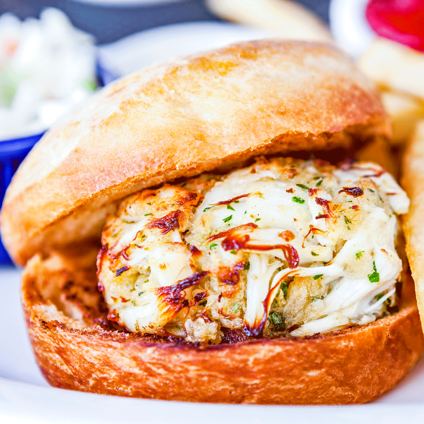 Jumbo lump crab cakes from Pig of the Month BBQ served as a burger with crispy bun and fresh toppings on a plate.