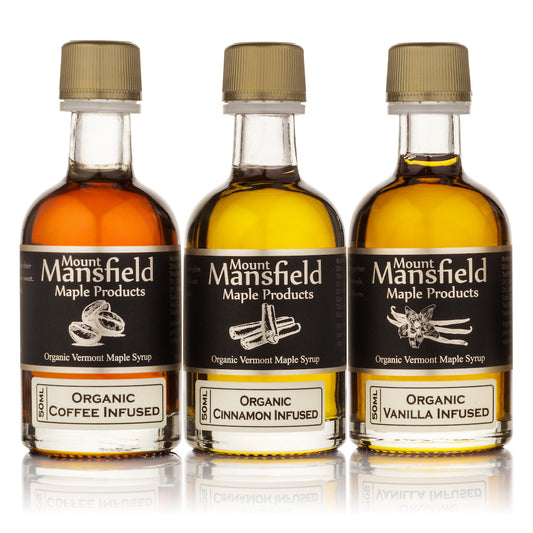 Three bottles of Mount Mansfield Maple Products infused Vermont maple syrup sampler set with labels and natural wood caps.