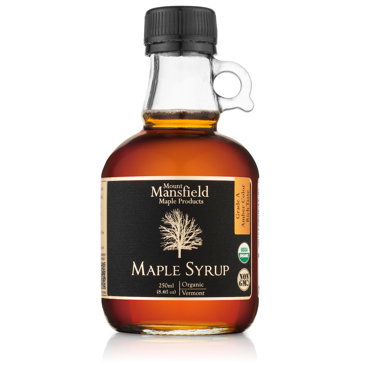 Glass jug of Mount Mansfield Organic Vermont Maple Syrup with a label, showcasing the rich amber color and smooth texture.