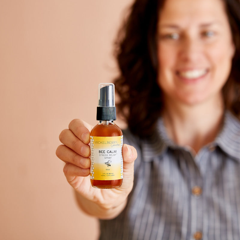 Mickelberry Gardens Bee Calm Stress Relief Spray in 2oz bottle held by a model, featuring honey tonic for relaxation and stress relief.