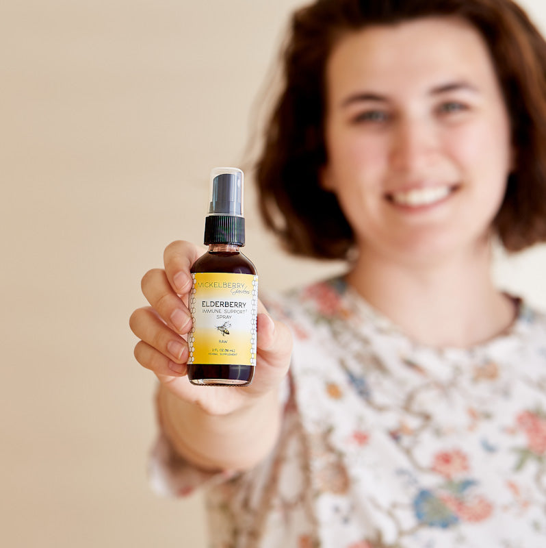 Mickelberry Gardens Elderberry Immune Support Spray in a 2oz bottle, held in hand, with honey tonic formula for immune health.