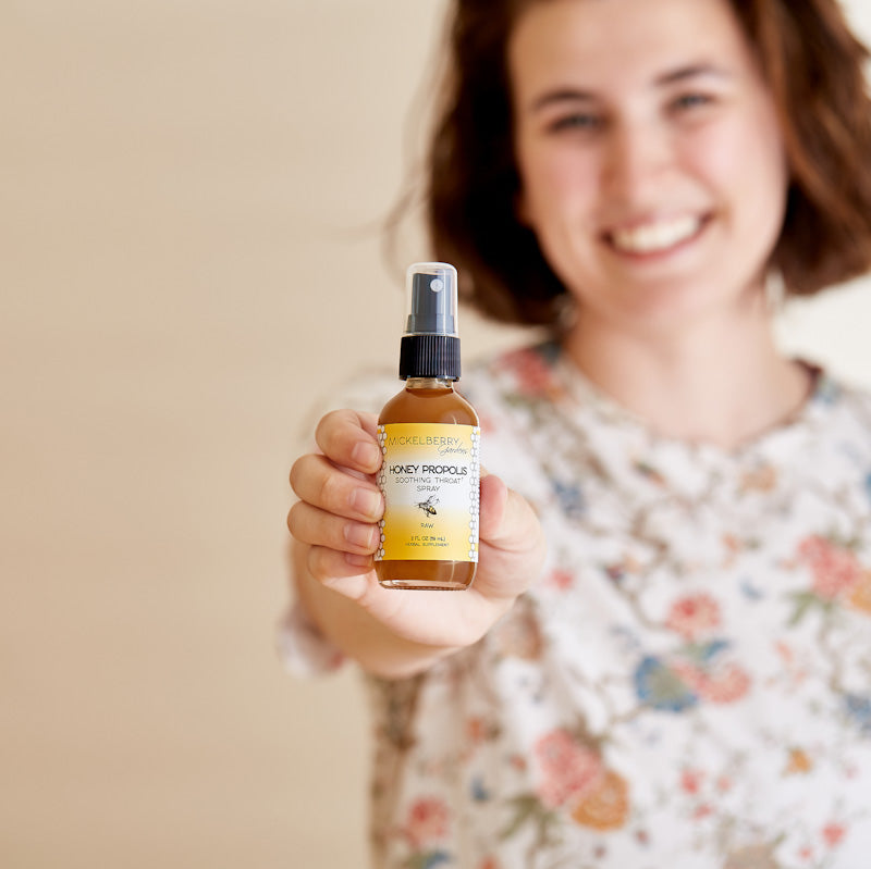 Mickelberry Gardens honey propolis throat spray in a bottle, held by a person, showcasing the honey tonic for soothing throat relief.