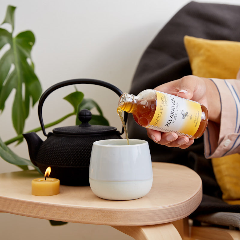 Pouring Mickelberry Gardens Relaxation Honey Tonic into a glass, showcasing the 4oz bottle of honey-based tonic drink.