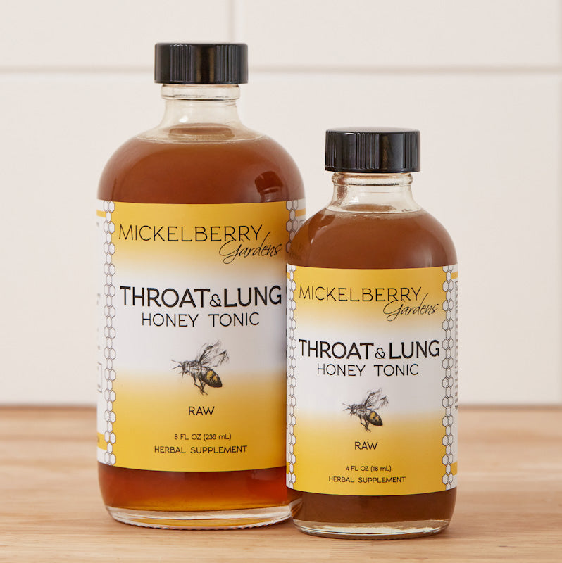 Family-sized bottle of Mickelberry Gardens Throat and Lung Honey Tonic with honey, herbs, and natural ingredients on a wooden table.