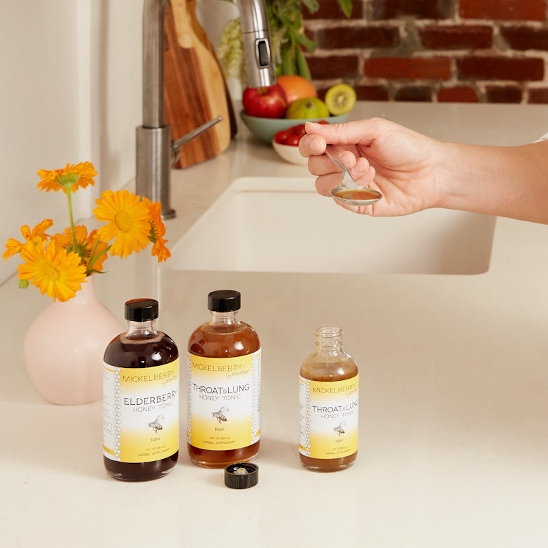 Spoonful of Mickelberry Gardens Throat and Lung Honey Tonic in a glass jar, showcasing a natural honey tonic for throat and lung health.