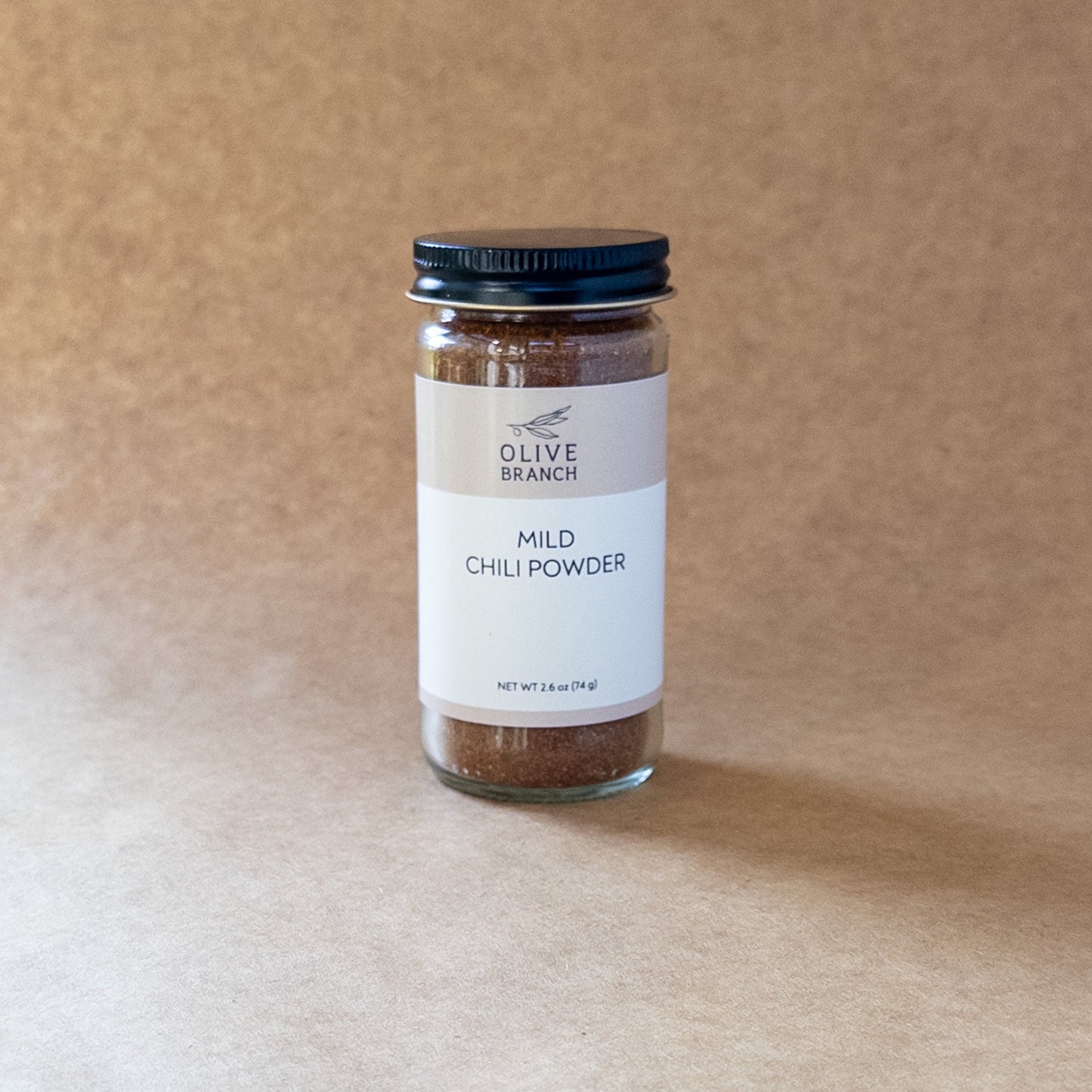 Olive Branch Oil & Spice mild chili powder blend in a glass jar, showing vibrant red chili flakes and spices.