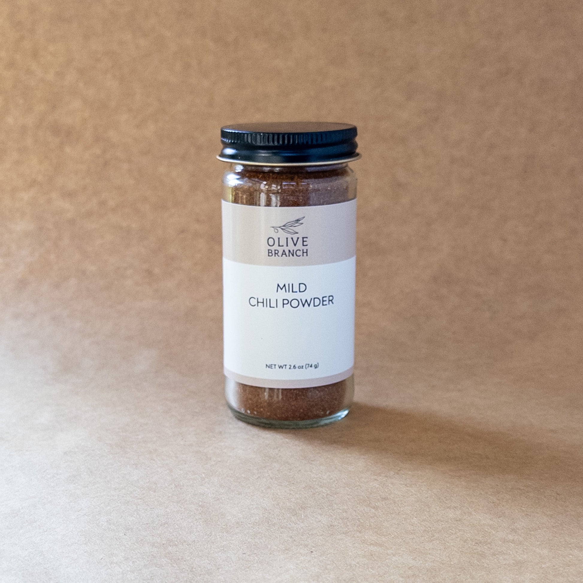 Olive Branch Oil & Spice mild chili powder blend in a glass jar, showing vibrant red chili flakes and spices.
