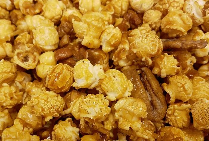 Millican Pecan caramel pecan popcorn in a large 1-gallon pail, showcasing crunchy pecans and golden caramel-coated popcorn.