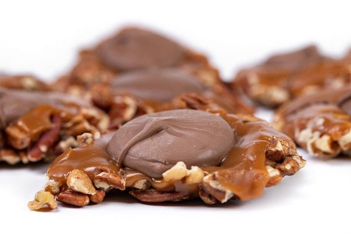 Milk chocolate Caramillicans pecan treats in a gift box by Millican Pecan, showcasing the chocolates with pecan pieces.