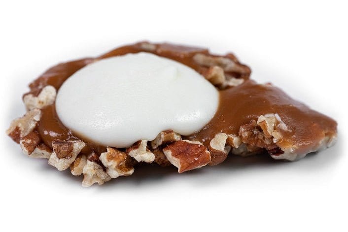 Individual white chocolate Caramillicans pecan treats by Millican Pecan, showcasing golden-brown pecan clusters coated in white chocolate.