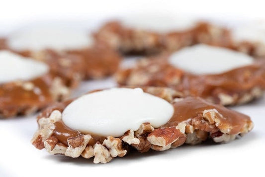 White Chocolate Caramillicans pecan treats in a gift box by Millican Pecan, showcasing white chocolate-coated pecan candies.