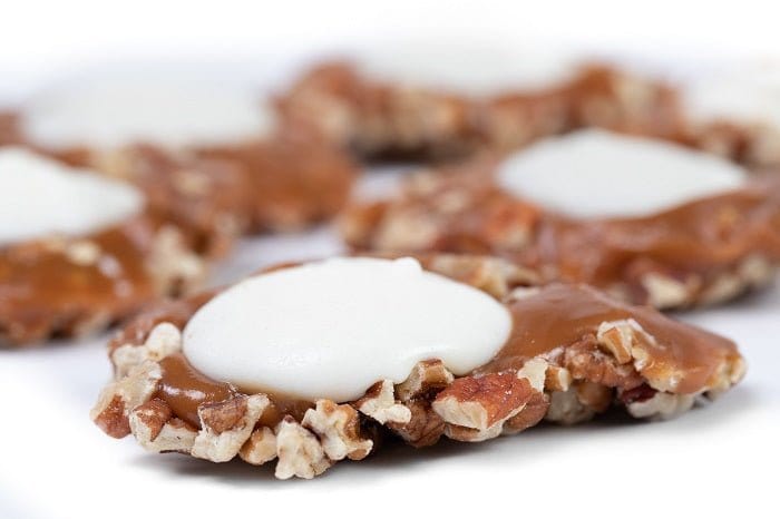 White Chocolate Caramillicans pecan treats by Millican Pecan, individual white chocolate-coated pecan candies on a white background.