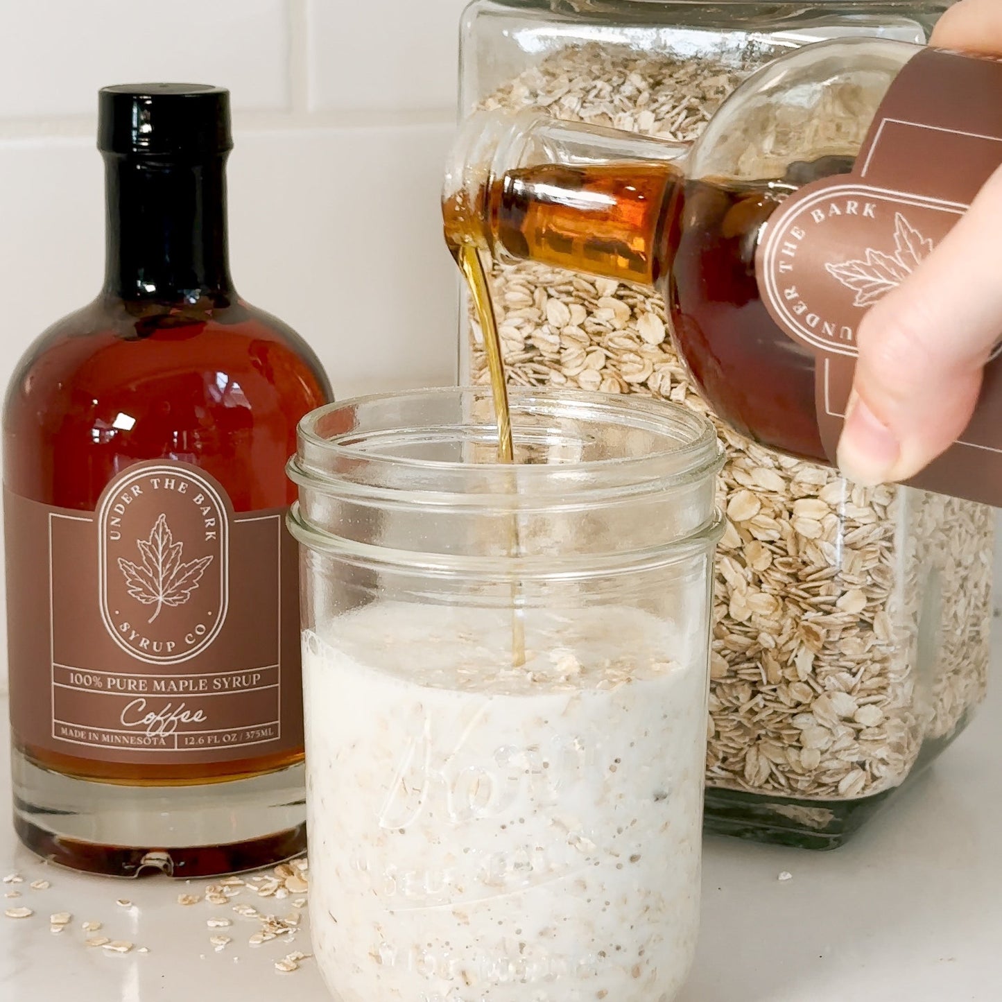 Creamy overnight oats topped with coffee maple syrup from Under The Bark Syrup Co, served in a glass jar with fresh fruit.
