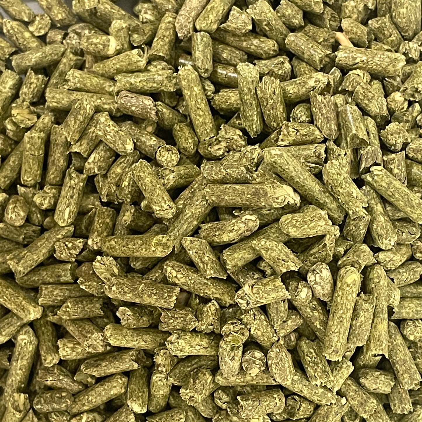 Natural alfalfa hay pellets from Rabbit Hole Hay, showing small, green, compressed alfalfa pellets in a clear container.