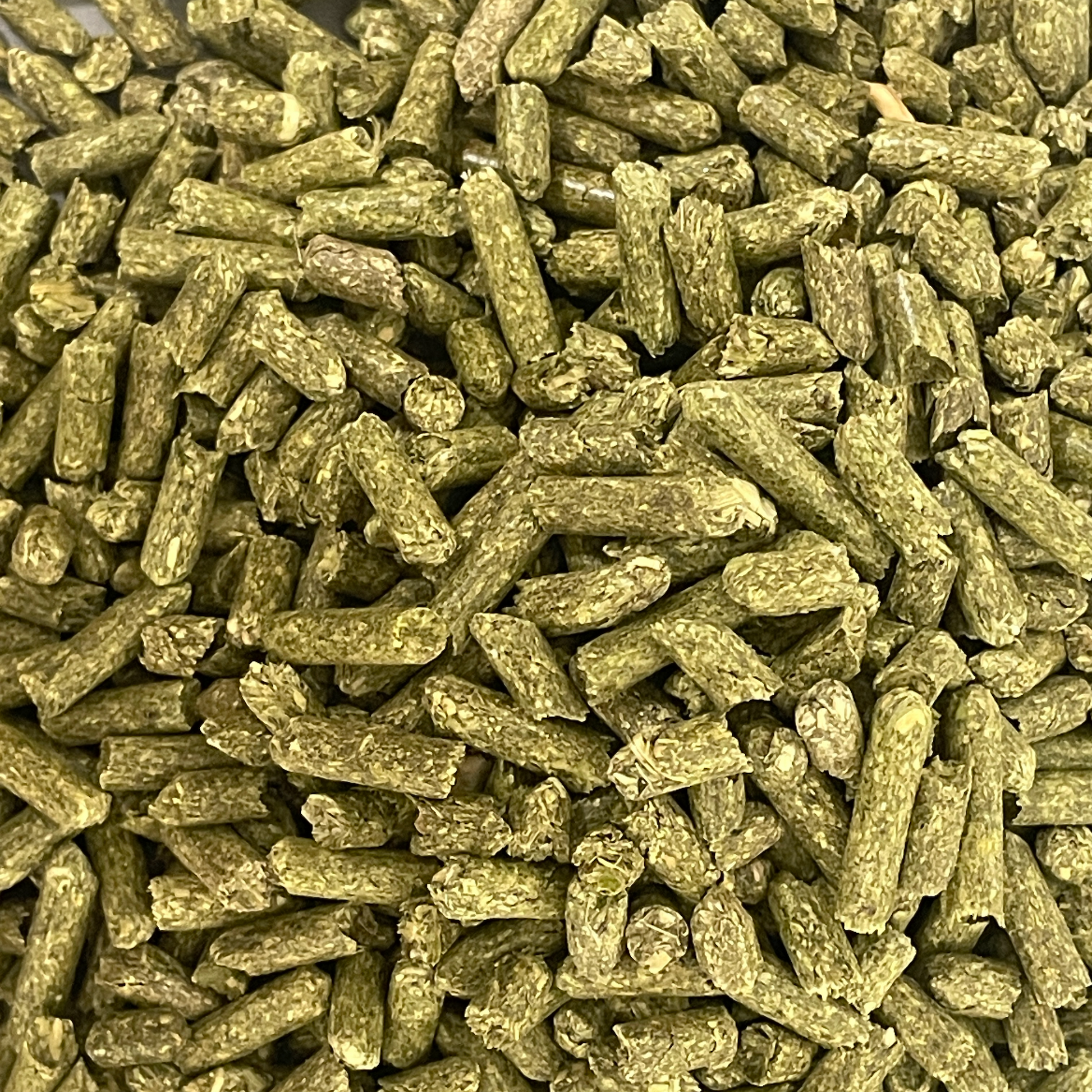 Natural alfalfa hay pellets from Rabbit Hole Hay, showing small, green, compressed alfalfa pellets in a clear container.